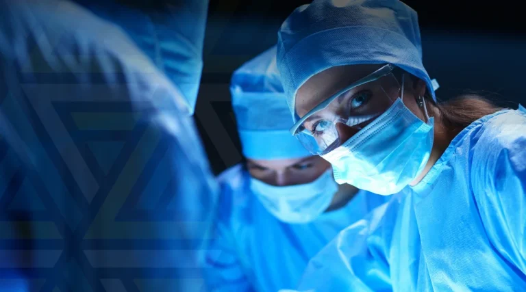 medici echipați în halate și echipament de protecție de culoare albastră, în cadrul unei operații chirurgicale